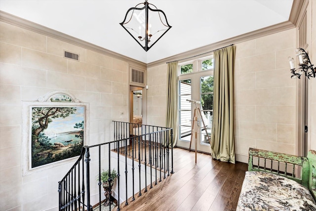 hallway featuring dark wood-type flooring, ornamental molding, french doors, and an inviting chandelier