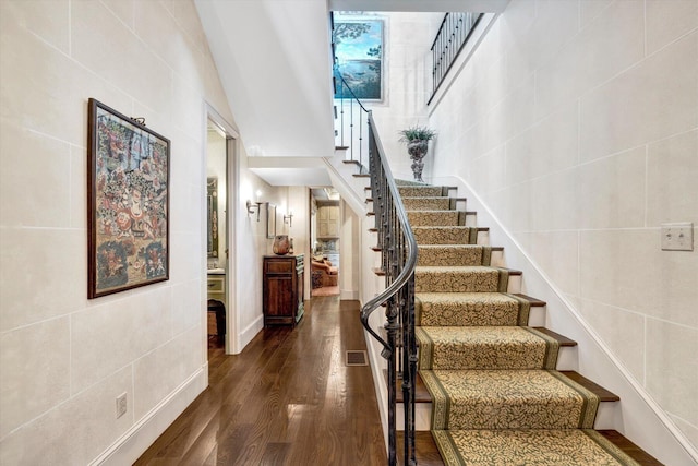 stairs with hardwood / wood-style flooring and a high ceiling