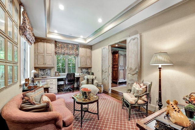 living area featuring hardwood / wood-style floors, a tray ceiling, and built in desk