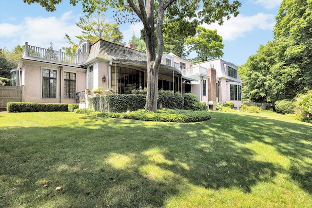 back of property with a balcony and a lawn