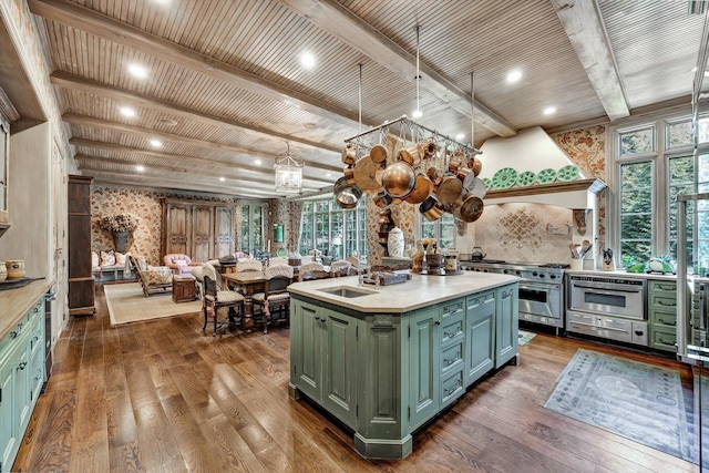 kitchen featuring sink, a center island with sink, range with two ovens, and dark hardwood / wood-style flooring