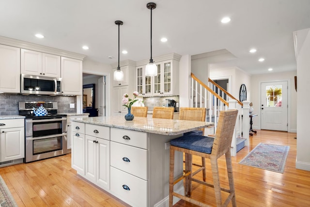 23 Ridgehill Ln, Sagamore Beach, MA 02562 - kitchen with stainless steel appliances, a kitchen breakfast bar, decorative backsplash, a kitchen island, and white cabinetry