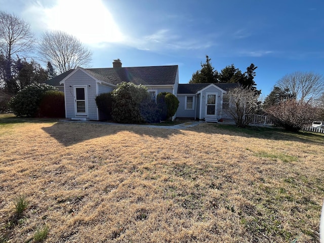 single story home featuring a front yard, entry steps, and a chimney