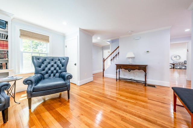 sitting room with light wood-type flooring and crown molding