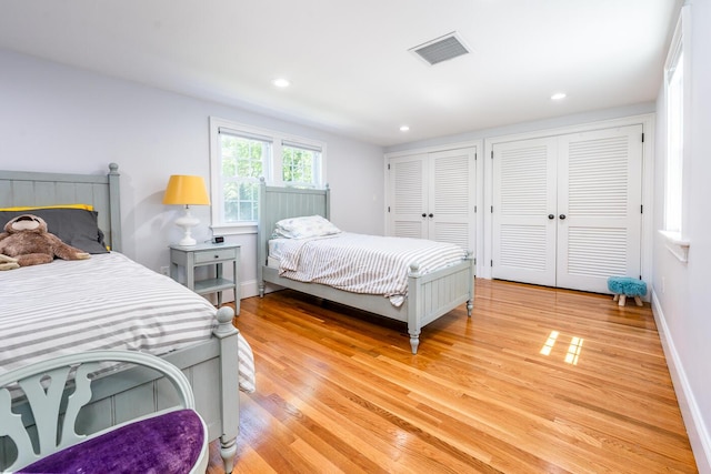 bedroom with light wood-type flooring and two closets