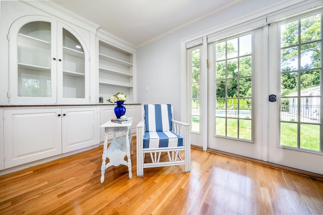 doorway to outside featuring built in features, crown molding, and light wood-type flooring