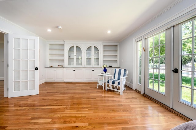 living area with ornamental molding and light wood-type flooring