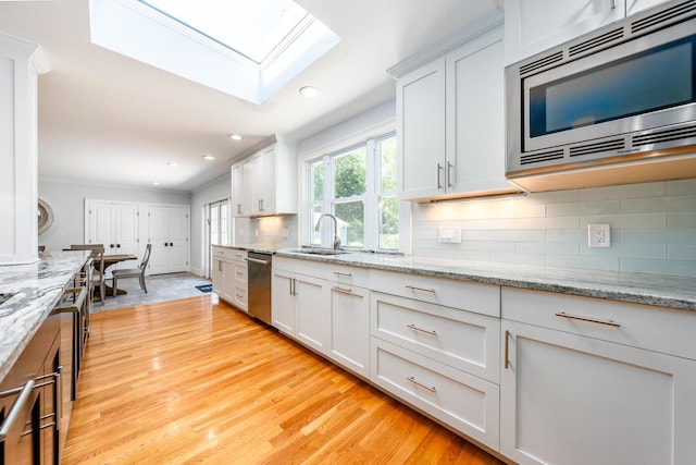 kitchen with sink, backsplash, white cabinetry, and appliances with stainless steel finishes