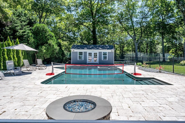 view of pool with a patio area, an outbuilding, and a fire pit