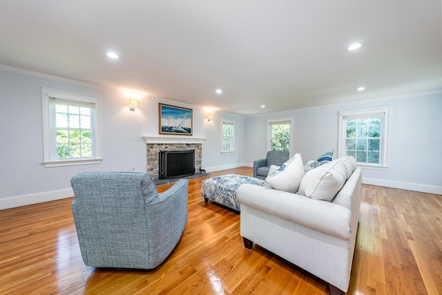 living room featuring a fireplace, light hardwood / wood-style floors, a wealth of natural light, and ornamental molding