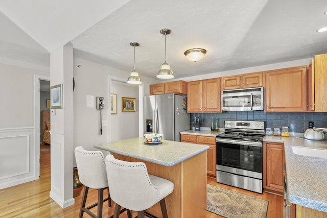 kitchen featuring a center island, light hardwood / wood-style floors, decorative backsplash, decorative light fixtures, and stainless steel appliances