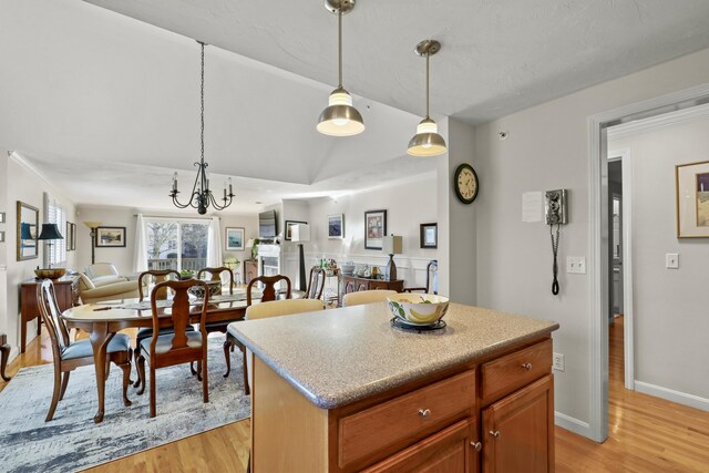 kitchen with light hardwood / wood-style floors, pendant lighting, a center island, and an inviting chandelier