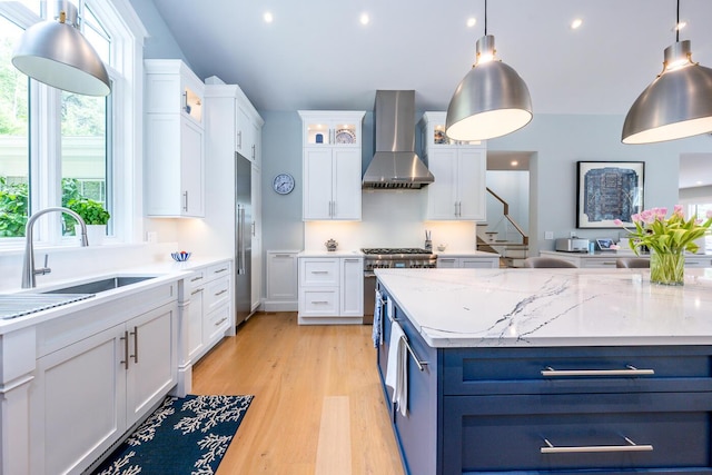 585 Santuit Rd, Cotuit, MA 02635 - kitchen featuring wall chimney exhaust hood, high end appliances, white cabinets, glass insert cabinets, and light wood finished floors
