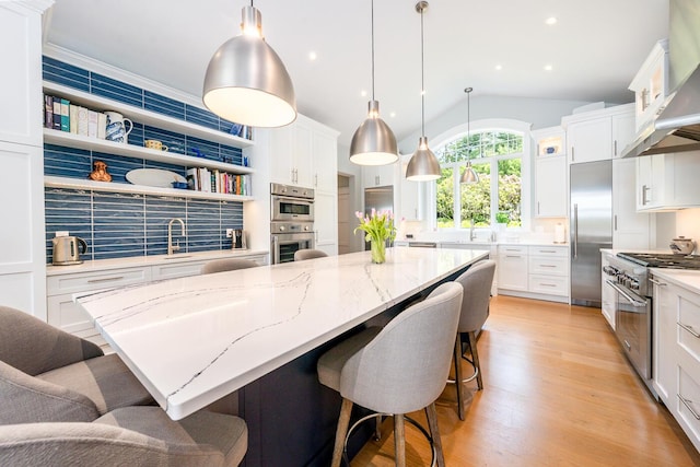 585 Santuit Rd, Cotuit, MA 02635 - kitchen with high end appliances, wall chimney range hood, a spacious island, white cabinetry, and vaulted ceiling