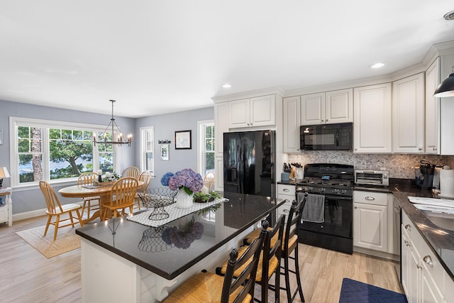 10 Stanley Rd, Mashpee, MA 02649 - kitchen featuring black appliances, a kitchen breakfast bar, decorative backsplash, light wood-style flooring, and a chandelier