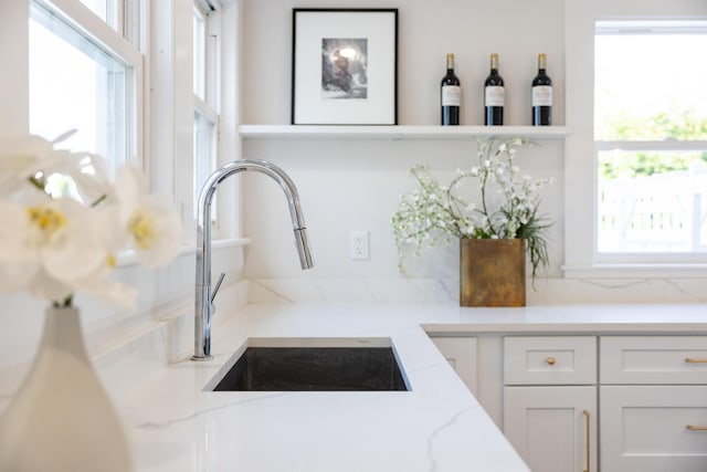 room details with sink, white cabinetry, and light stone counters