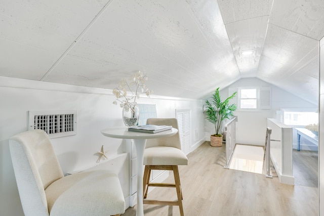 dining space featuring light hardwood / wood-style floors and lofted ceiling