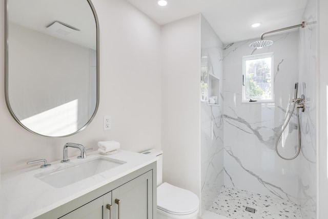 bathroom featuring vanity, toilet, and tiled shower