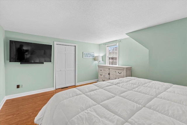 bedroom with light wood-style floors, a closet, baseboards, and a textured ceiling