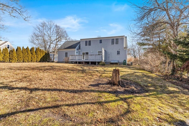 back of property featuring a deck and a lawn