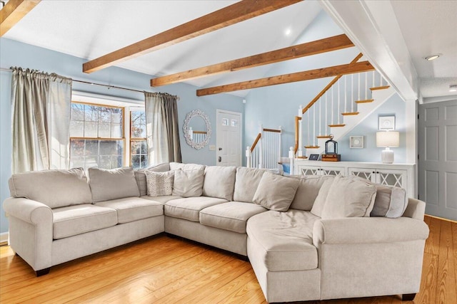 living area with vaulted ceiling with beams, stairway, and wood finished floors