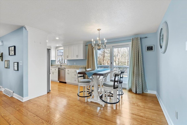 dining room with visible vents, baseboards, light wood-style flooring, a textured ceiling, and a notable chandelier