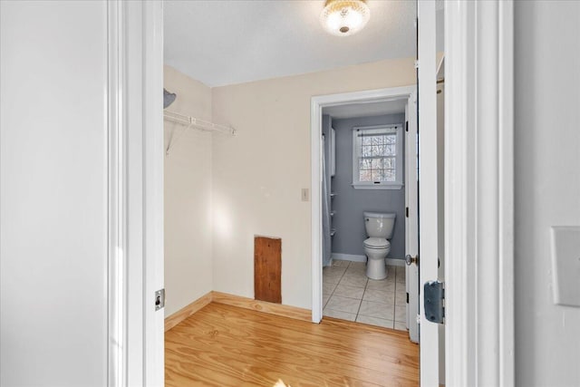 bathroom featuring baseboards, a textured ceiling, toilet, and wood finished floors