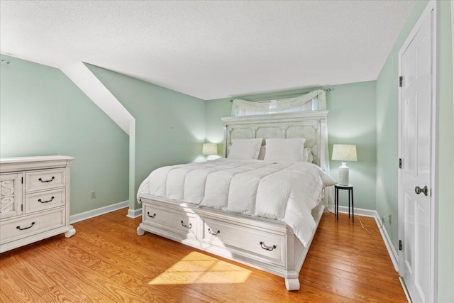 bedroom featuring baseboards, a textured ceiling, and light wood finished floors