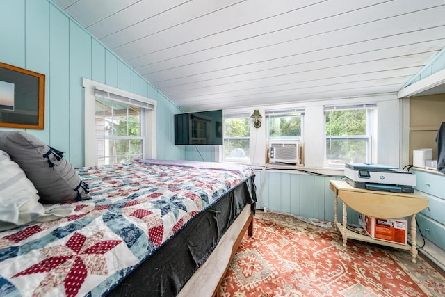 bedroom with cooling unit, lofted ceiling, and wooden walls