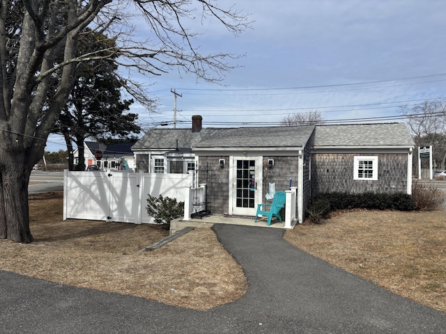 view of front of home featuring a shingled roof and fence