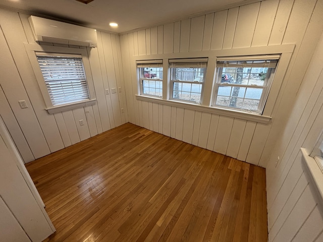 spare room featuring plenty of natural light, hardwood / wood-style floors, and a wall mounted AC