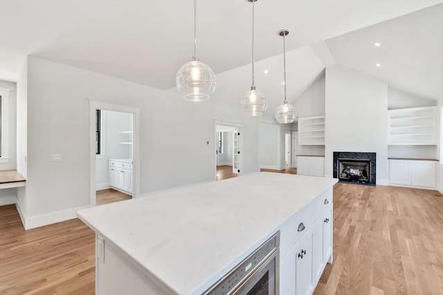 kitchen featuring pendant lighting, light wood-type flooring, white cabinetry, a center island, and lofted ceiling