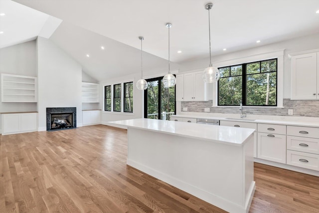 kitchen featuring sink, white cabinetry, vaulted ceiling, and a kitchen island