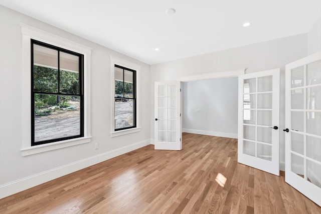 spare room featuring french doors and light wood-type flooring