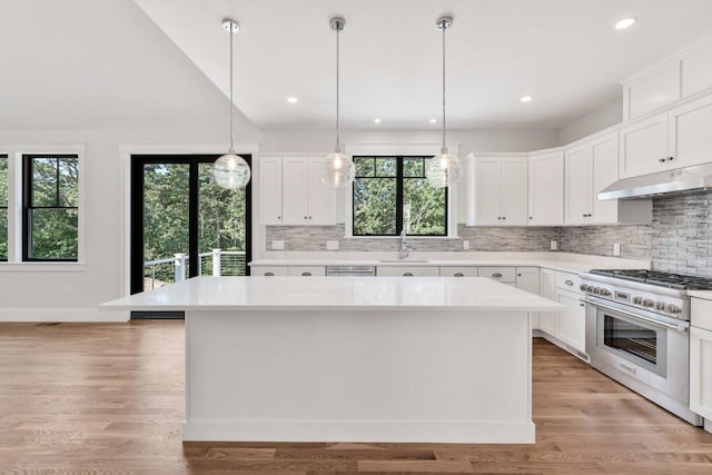 kitchen featuring sink, a center island, white cabinets, and stainless steel range