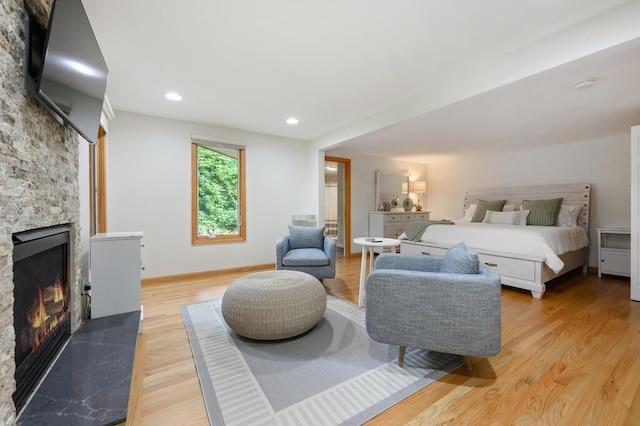 bedroom featuring light hardwood / wood-style flooring and a stone fireplace