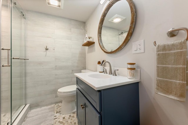 bathroom with toilet, a shower with shower door, and vanity