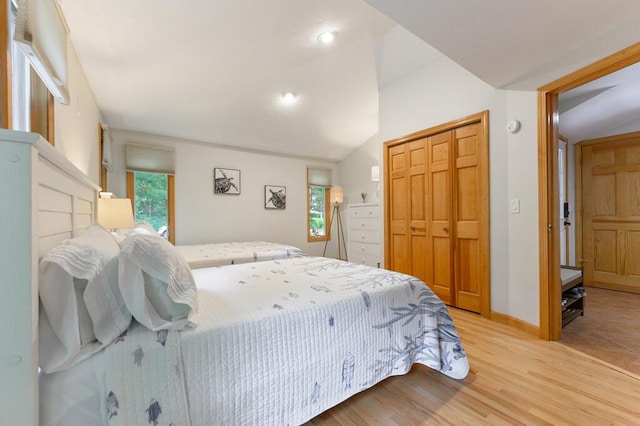 bedroom with a closet, light wood-type flooring, and lofted ceiling