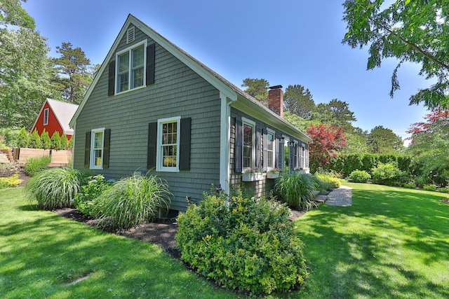 view of side of property featuring a chimney and a lawn
