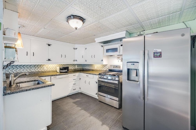 281 Gosnold St, Hyannis, MA 02601 - kitchen with appliances with stainless steel finishes, a sink, white cabinets, decorative backsplash, and dark stone counters
