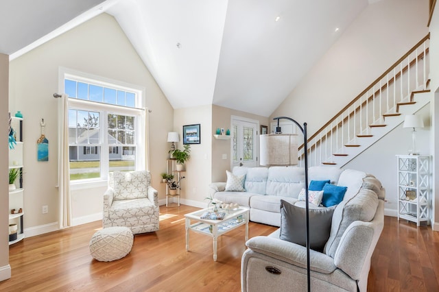 living area featuring baseboards, stairway, high vaulted ceiling, and wood finished floors