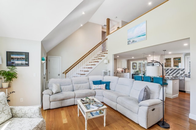 living room featuring high vaulted ceiling, stairway, wood finished floors, and recessed lighting