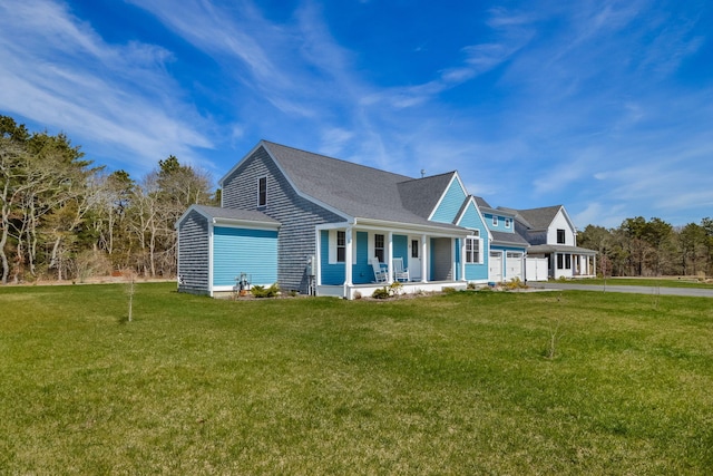 view of front facade featuring covered porch, an attached garage, driveway, a front yard, and a shingled roof