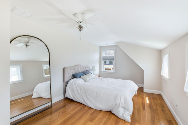 bedroom featuring ceiling fan, baseboards, light wood-type flooring, and multiple windows
