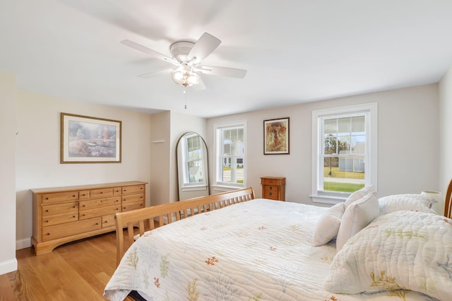 bedroom featuring ceiling fan, light wood-style flooring, and baseboards