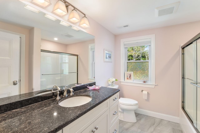 full bath with baseboards, toilet, vanity, and visible vents