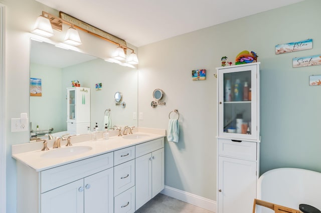 bathroom with double vanity, baseboards, a freestanding bath, and a sink
