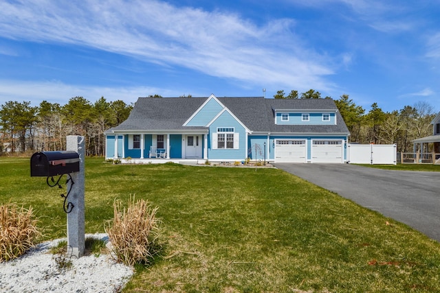 view of front of house with driveway, fence, covered porch, a front yard, and roof with shingles