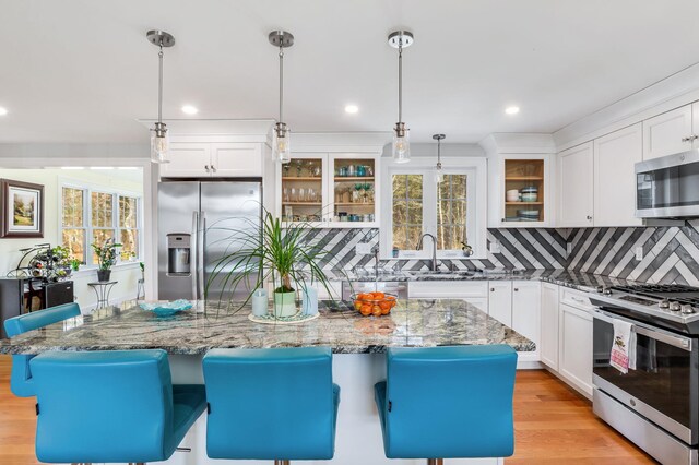 kitchen with glass insert cabinets, a sink, white cabinetry, decorative backsplash, and appliances with stainless steel finishes