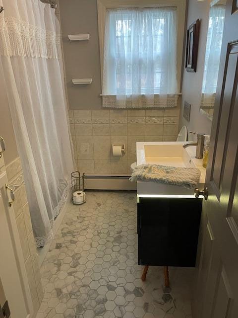 bathroom with vanity, tile walls, a baseboard radiator, and walk in shower